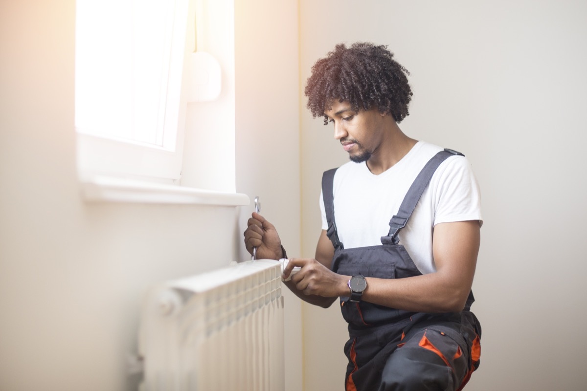 man fixing radiator heating system in home