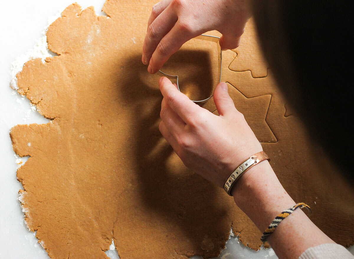 rolled out gingerbread dough on a marble counter, cutting cookies