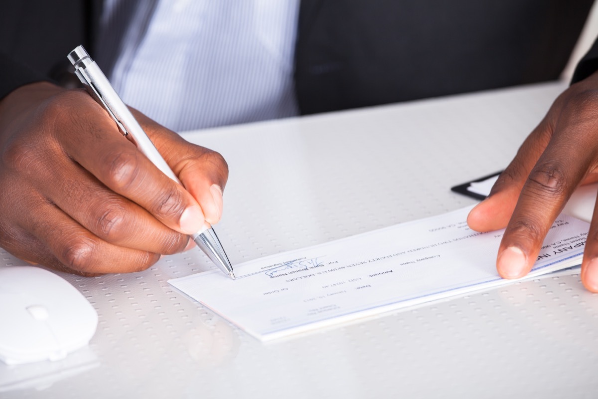 Close-up Of Human Hand Writing On Cheque