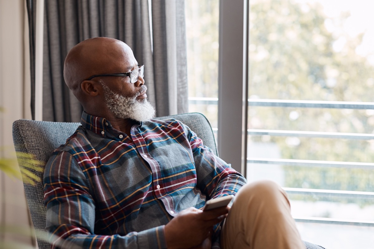 Shot of a mature man looking thoughtful while using a cellphone at home