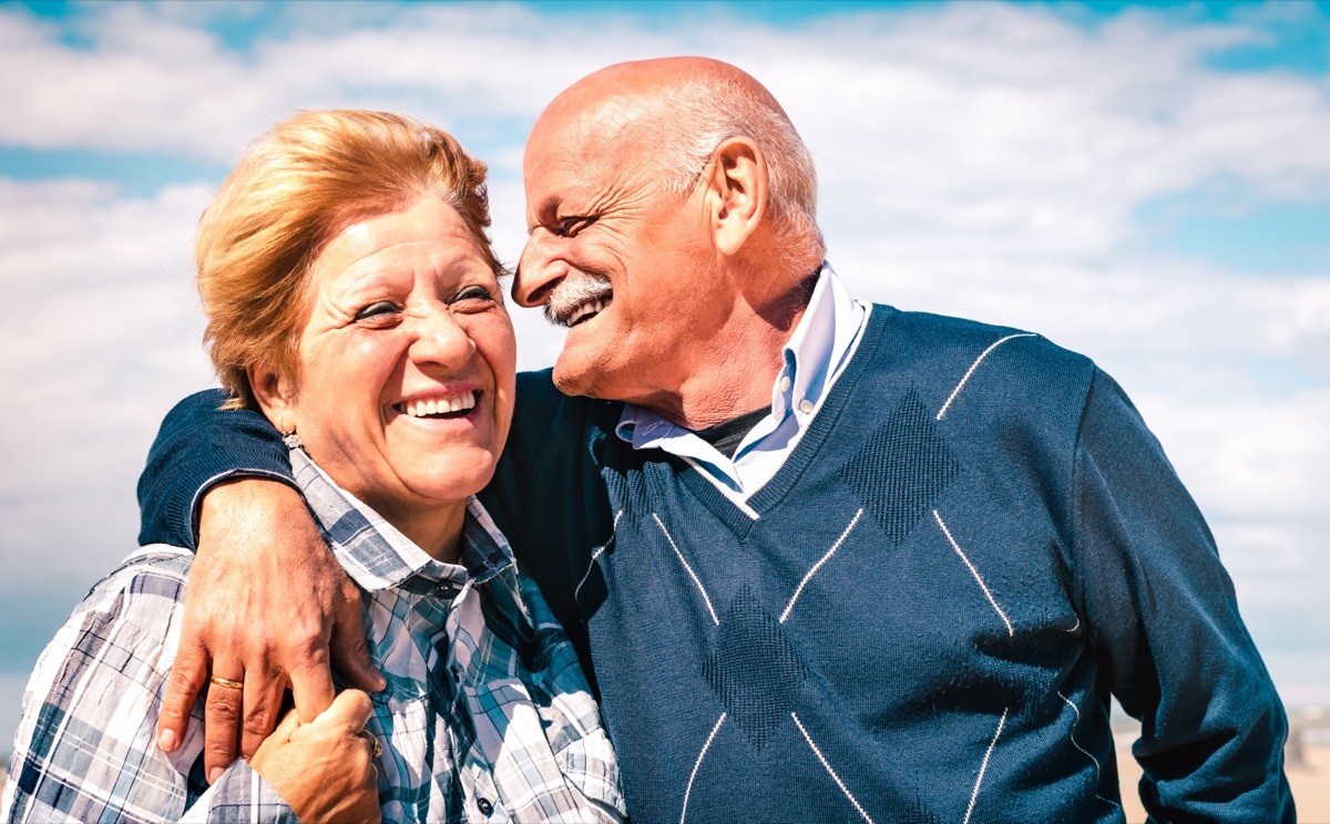 happy senior man and woman whispering to one another