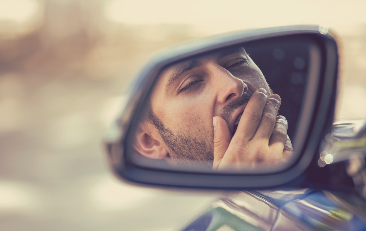 sleepy tired fatigued yawning exhausted young man driving his car