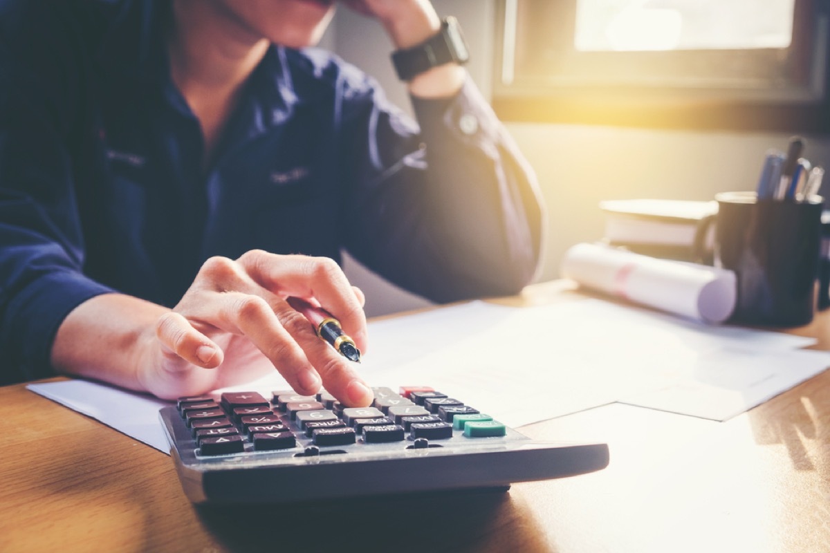 close up of man on calculator doing taxes at his desk