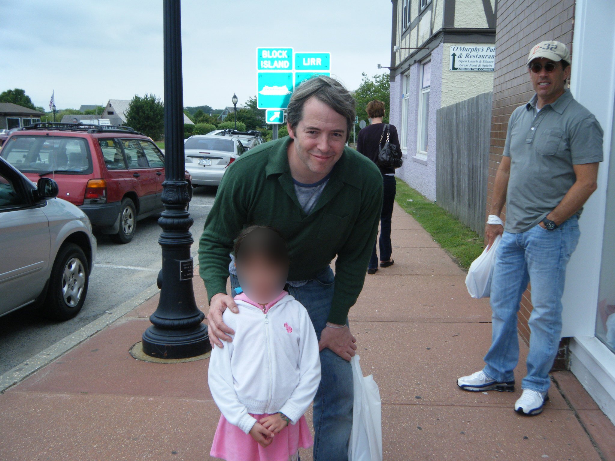 photo of matthew broderick posing with child, with jerry seinfeld in the background.