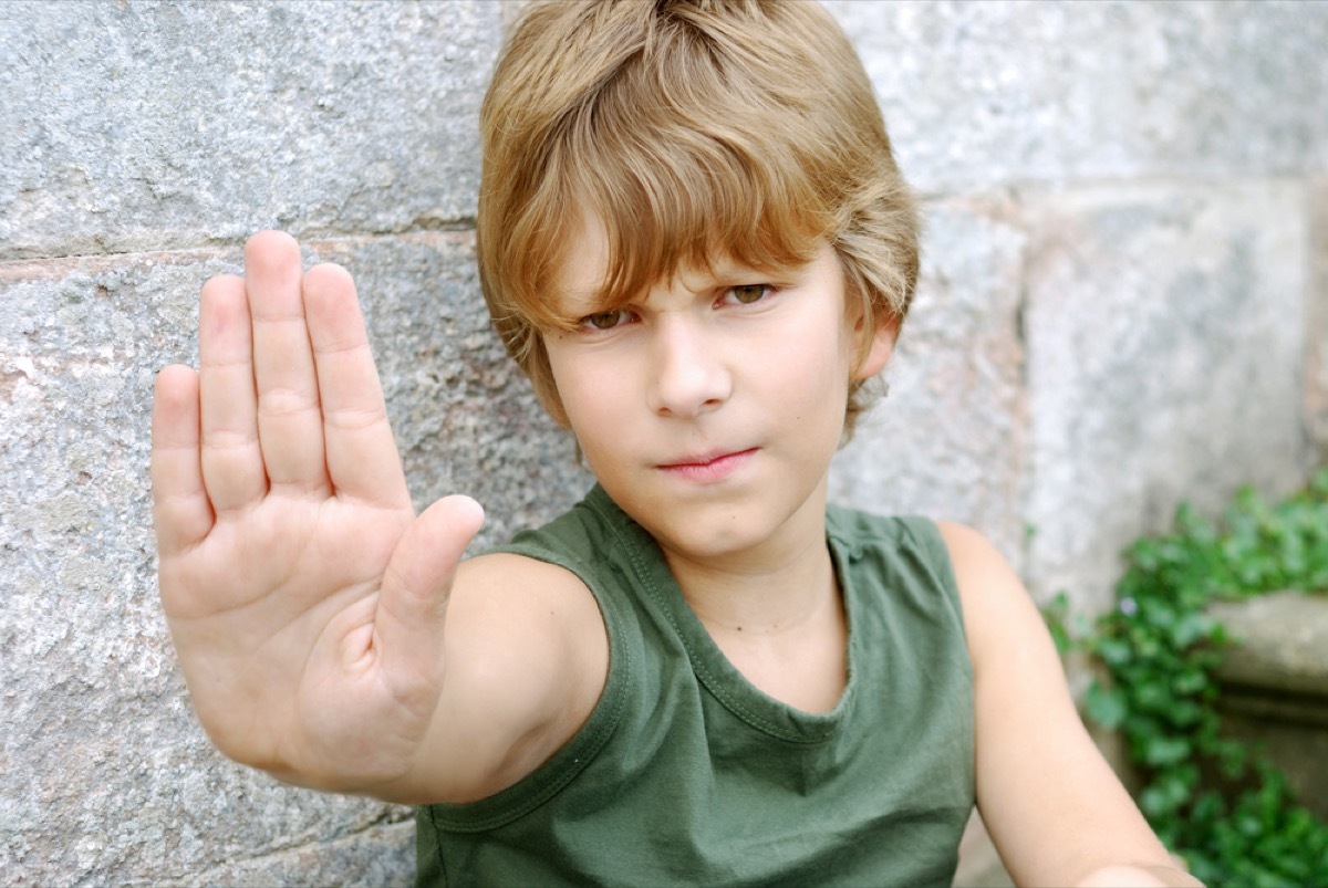 young boy putting hand up with palm out, skills parents should teach kids