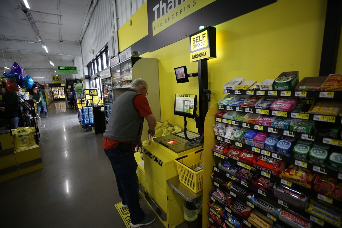 A senior man using the self-checkout kiosk at Dollar General