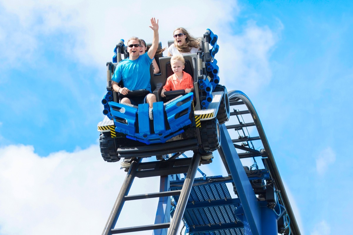 family having fun riding a rollercoaster at a theme park