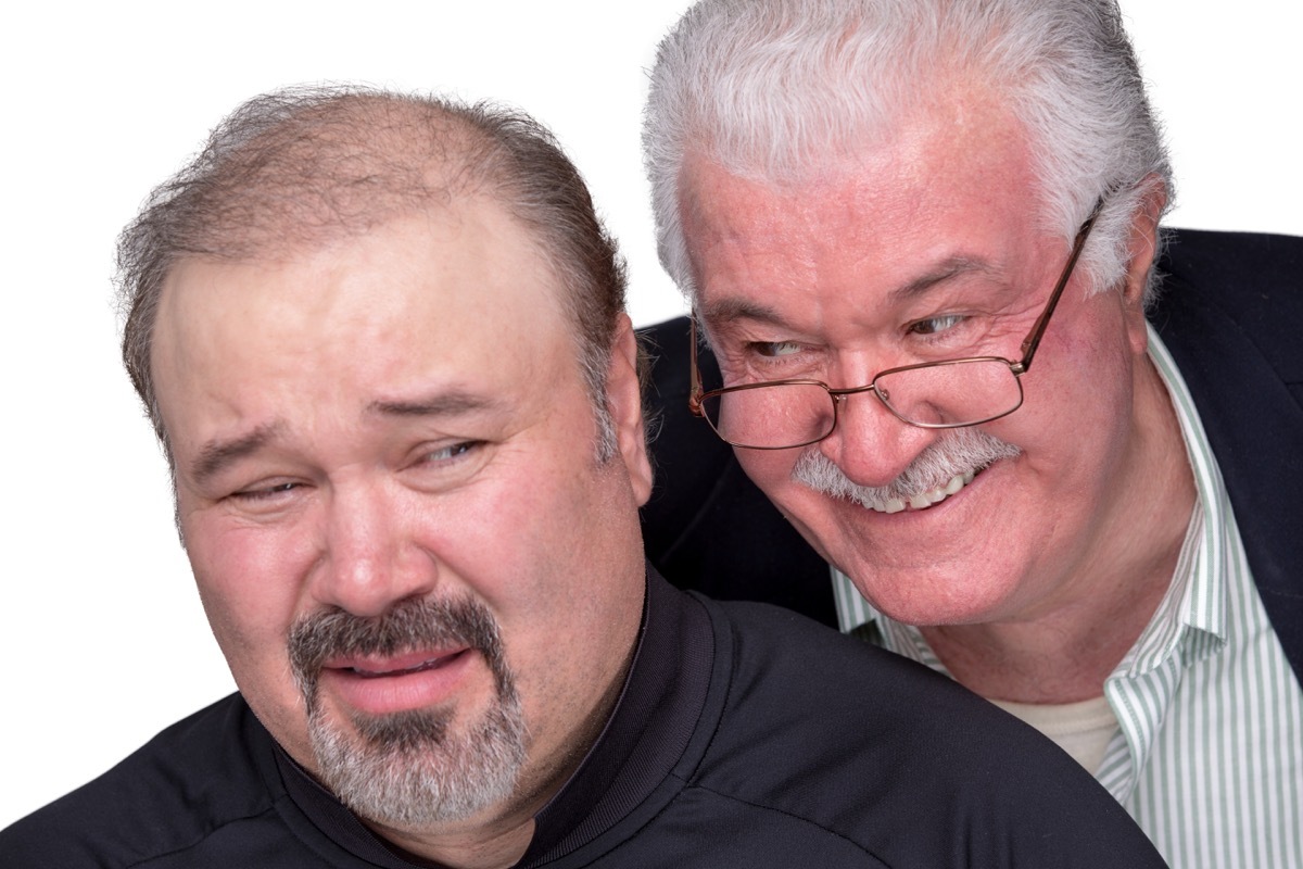 Man leaning over another man's shoulder, talking too closely