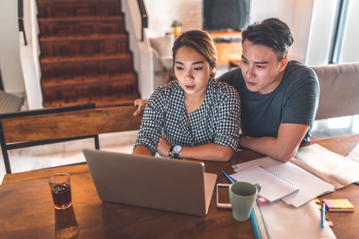 Young man and woman sitting at table with laptop and paperwork