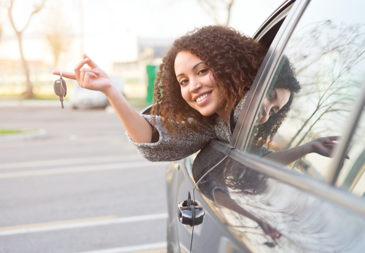 Woman leaning out of new car holding keys