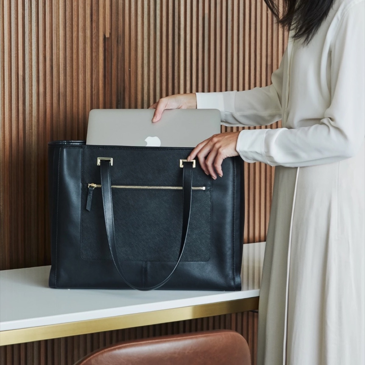 woman putting mac laptop into lo & sons tote