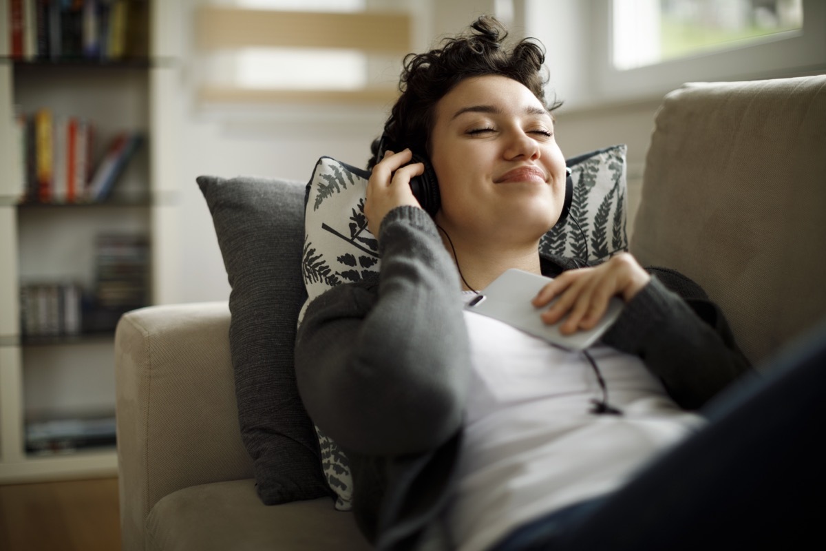 woman listening to new music while laying on the couch