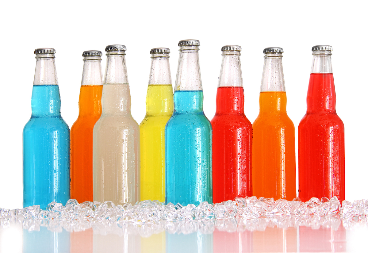 Bottles of multi-color wine cooler drinks with ice on white background