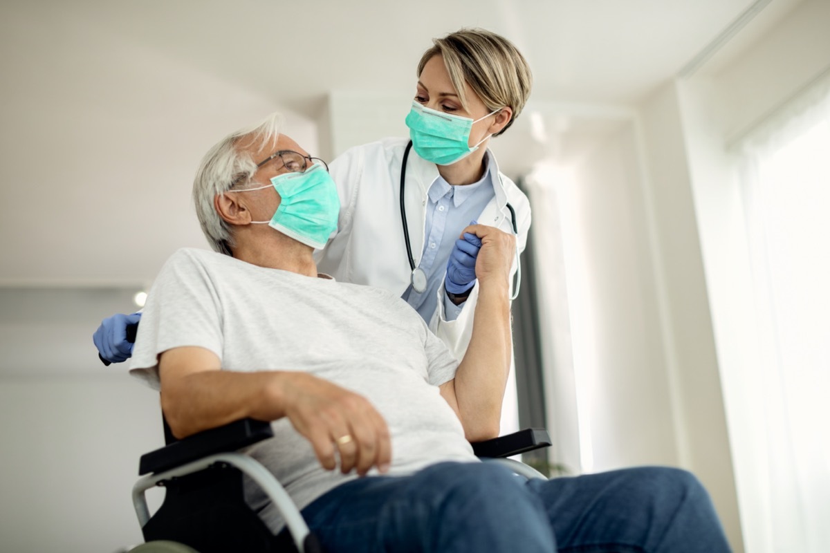 female doctor holding hands with senior man in wheelchair