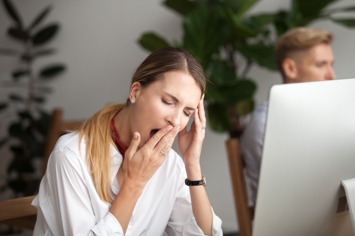 Woman Yawning at Her Desk