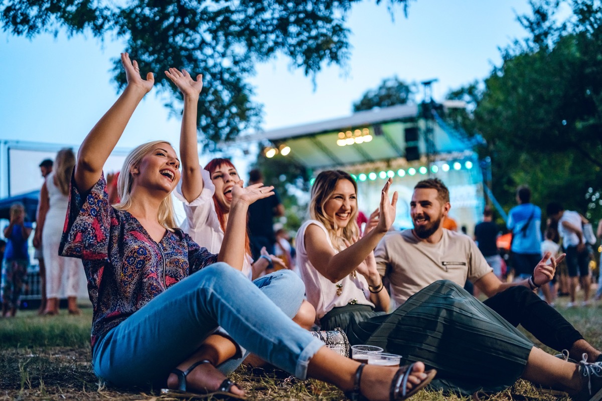 four young people sitting outside at an outdoor concert