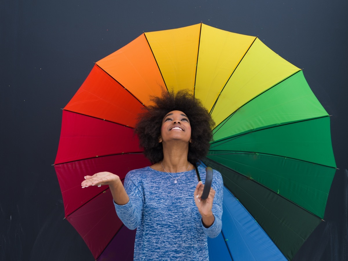 Young woman holding rainbow umbrella