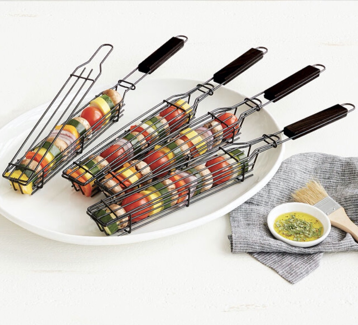 kabob grilling baskets on white plate next to small dish of oil