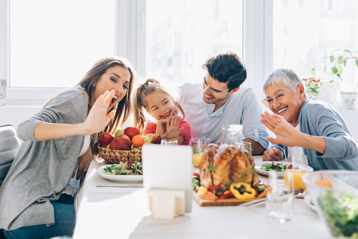 A multi-generational family uses a tablet to video conference during their Thanksgiving dinner