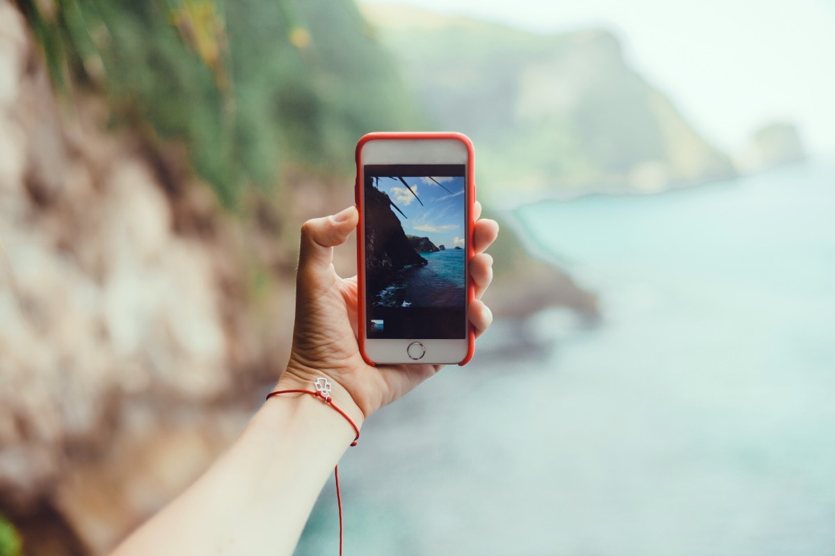 woman taking a photo of a beautiful landscape on her smartphone