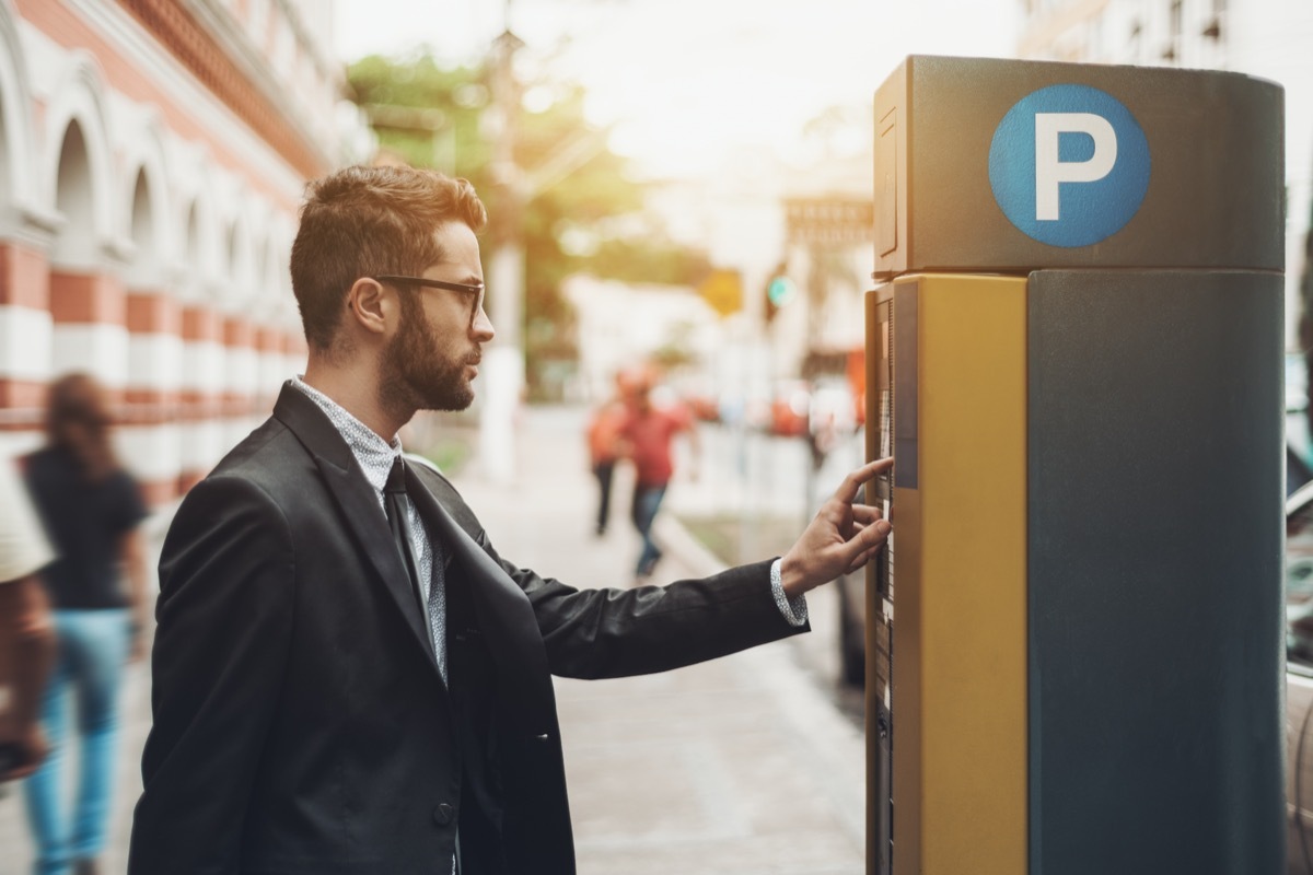 man paying at parking meter