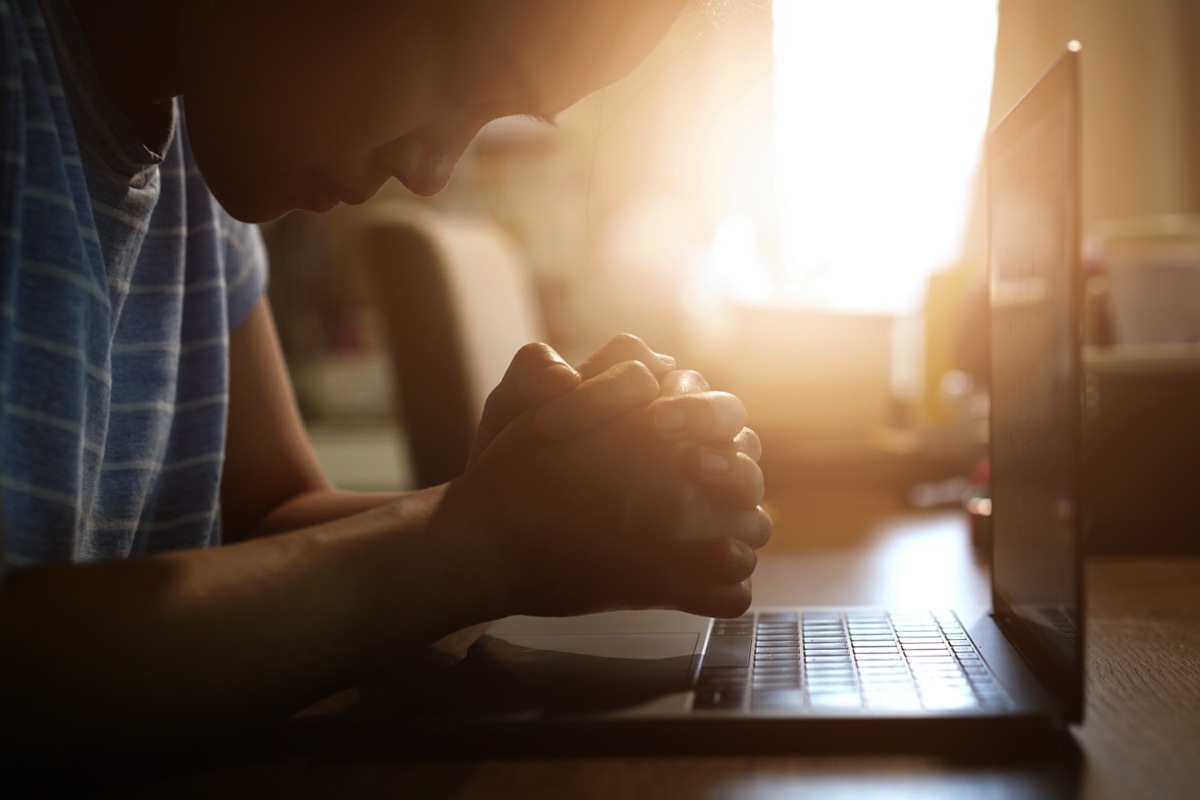 woman praying in darkness with computer laptop 