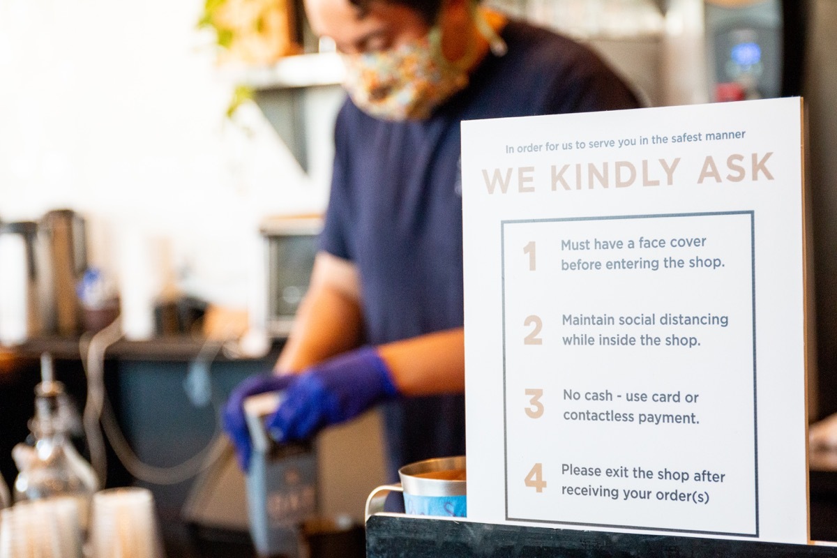 Man working in a coffee shop wearing a mask