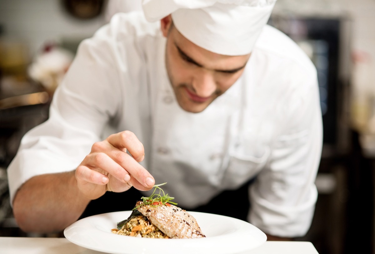 Male chef garnishing dish