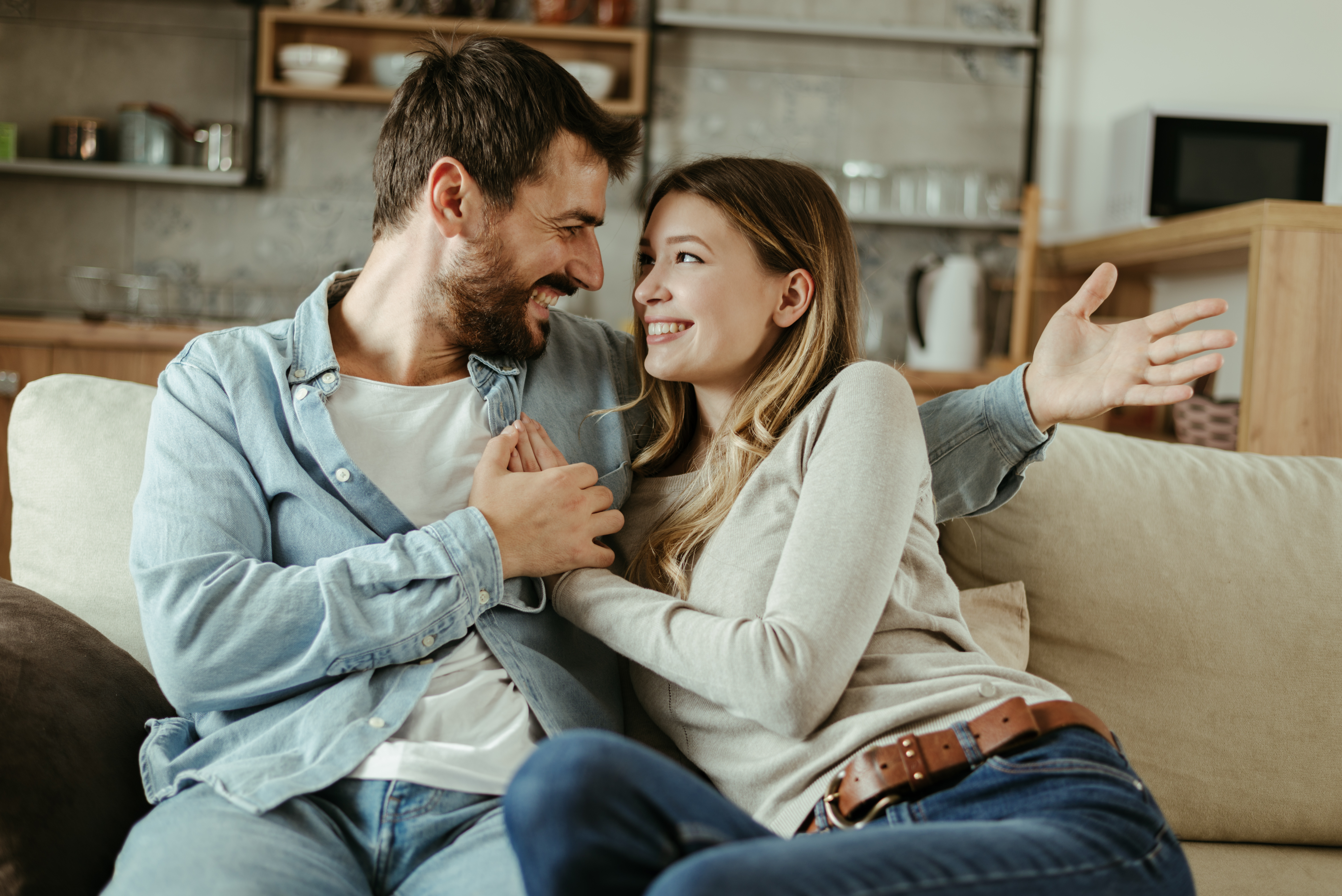 couple sitting on a couch holding hands asking each other random questions