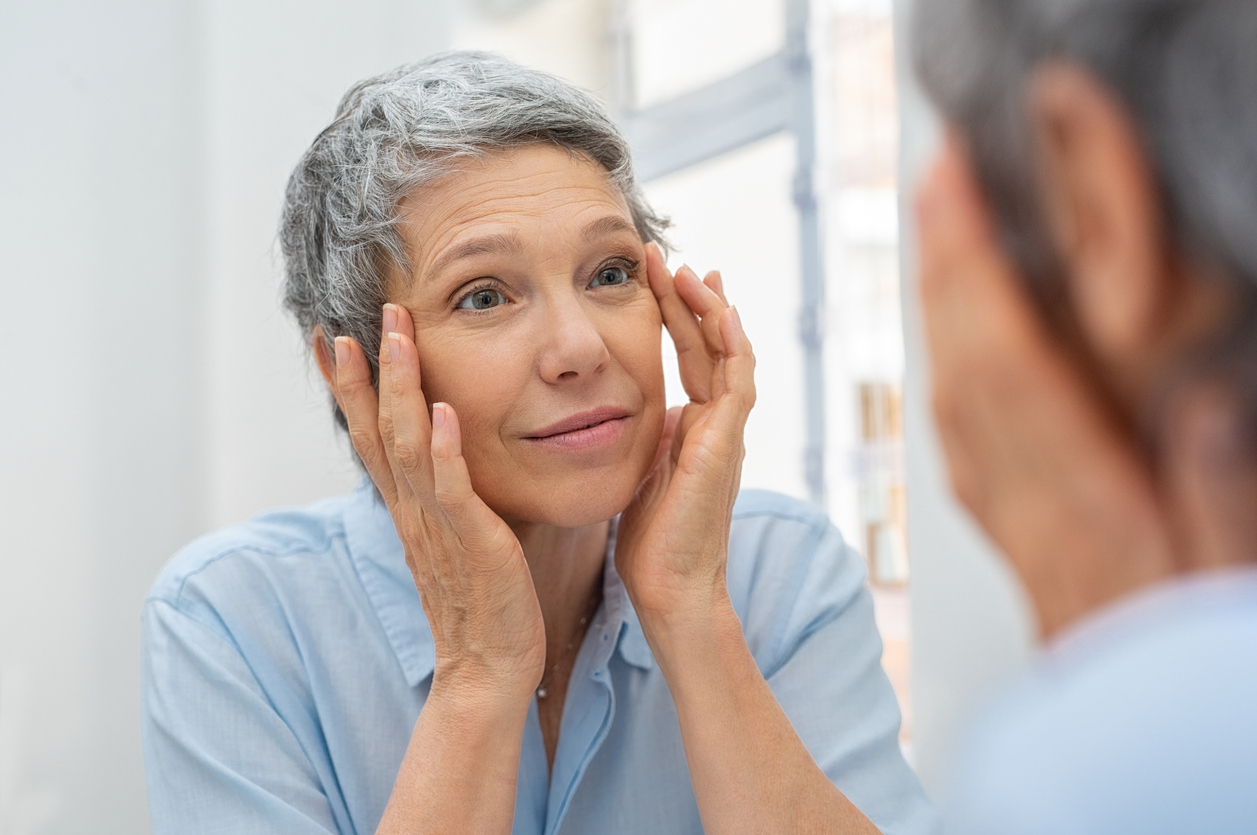 Older woman looking in bathroom mirror.