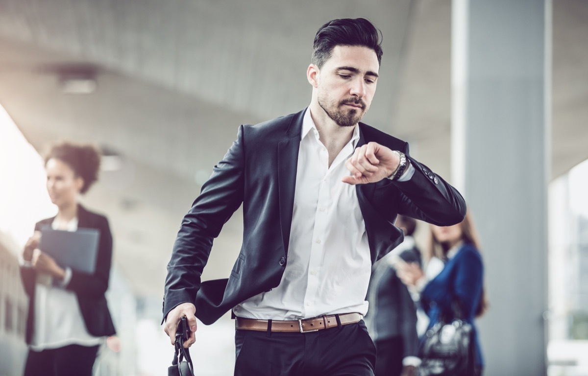 Businessman walking fast and checking the Time