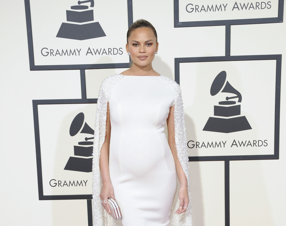 Chrissy Teigen at the Grammys red carpet wearing a white dress