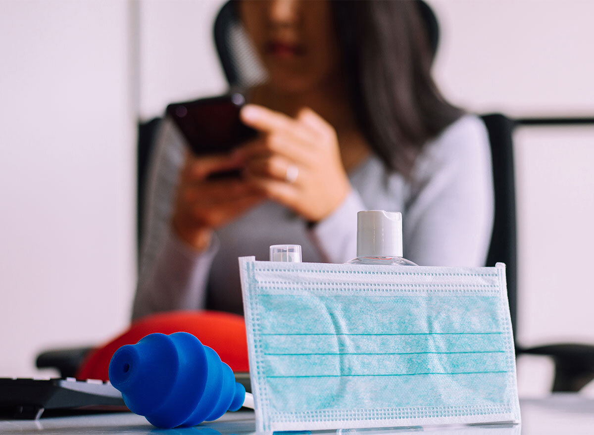 face mask on table woman looking at phone