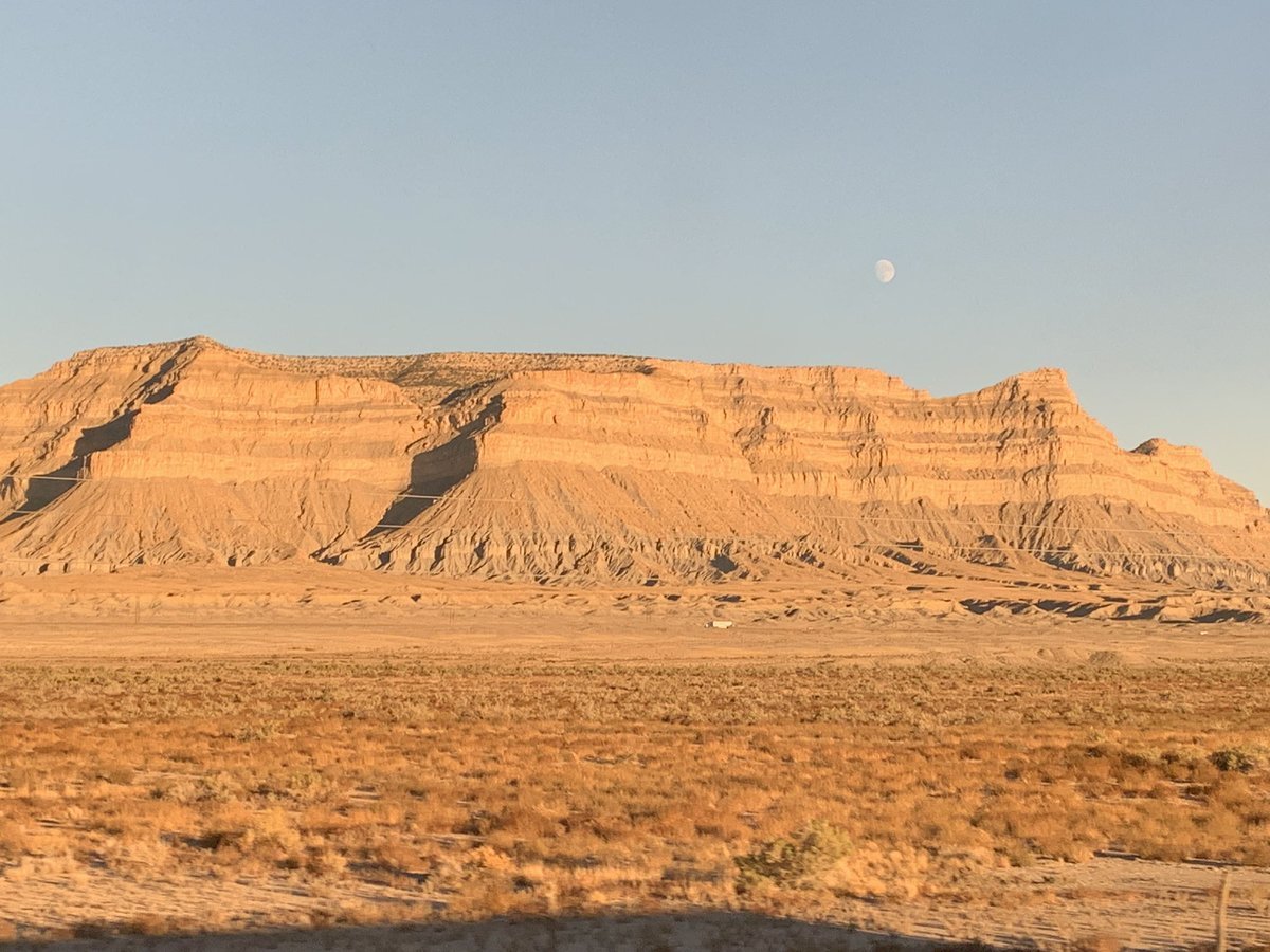 a mesa in utah with the moon above it