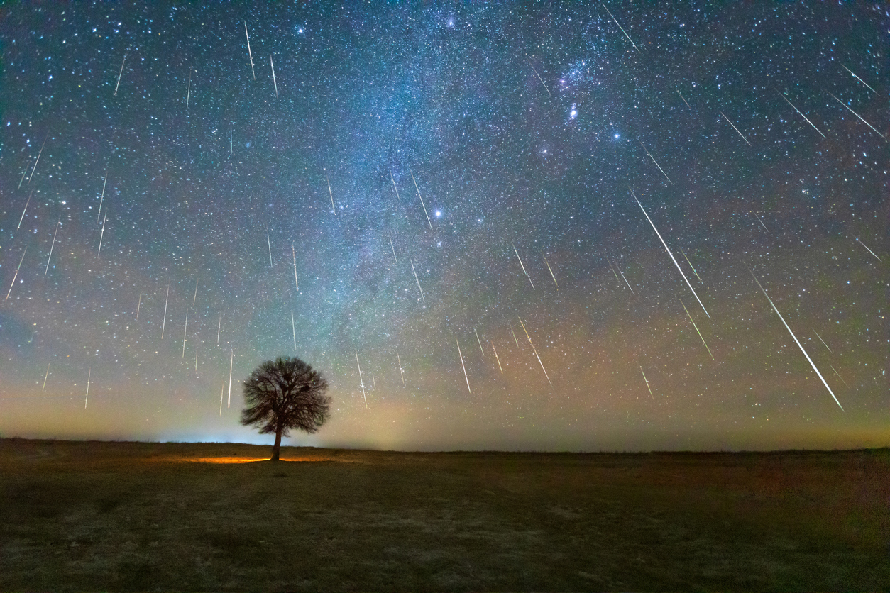 A wide shot of the night sky with dozens of meteors streaking