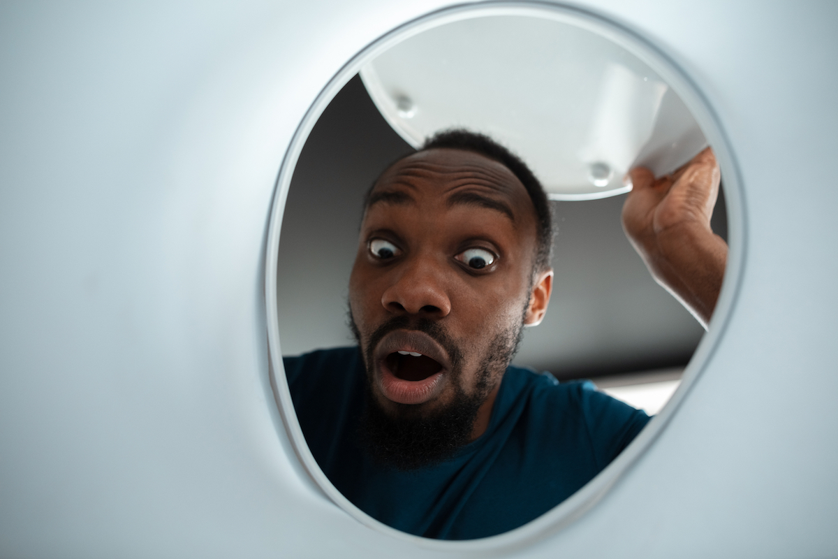 Looking up at a surprised man peering into his toilet bowl