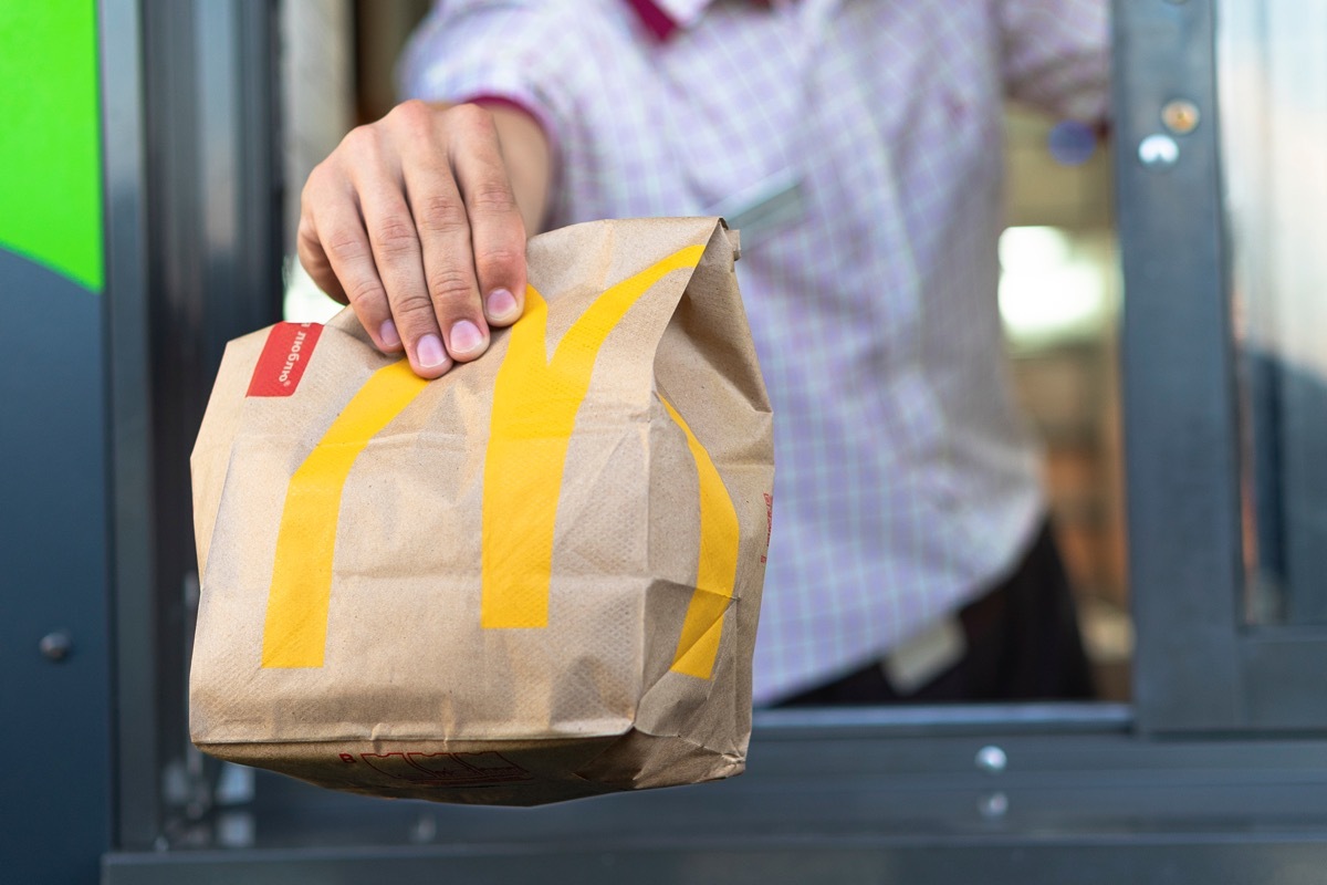 McDonalds worker hands order out the drive thru window