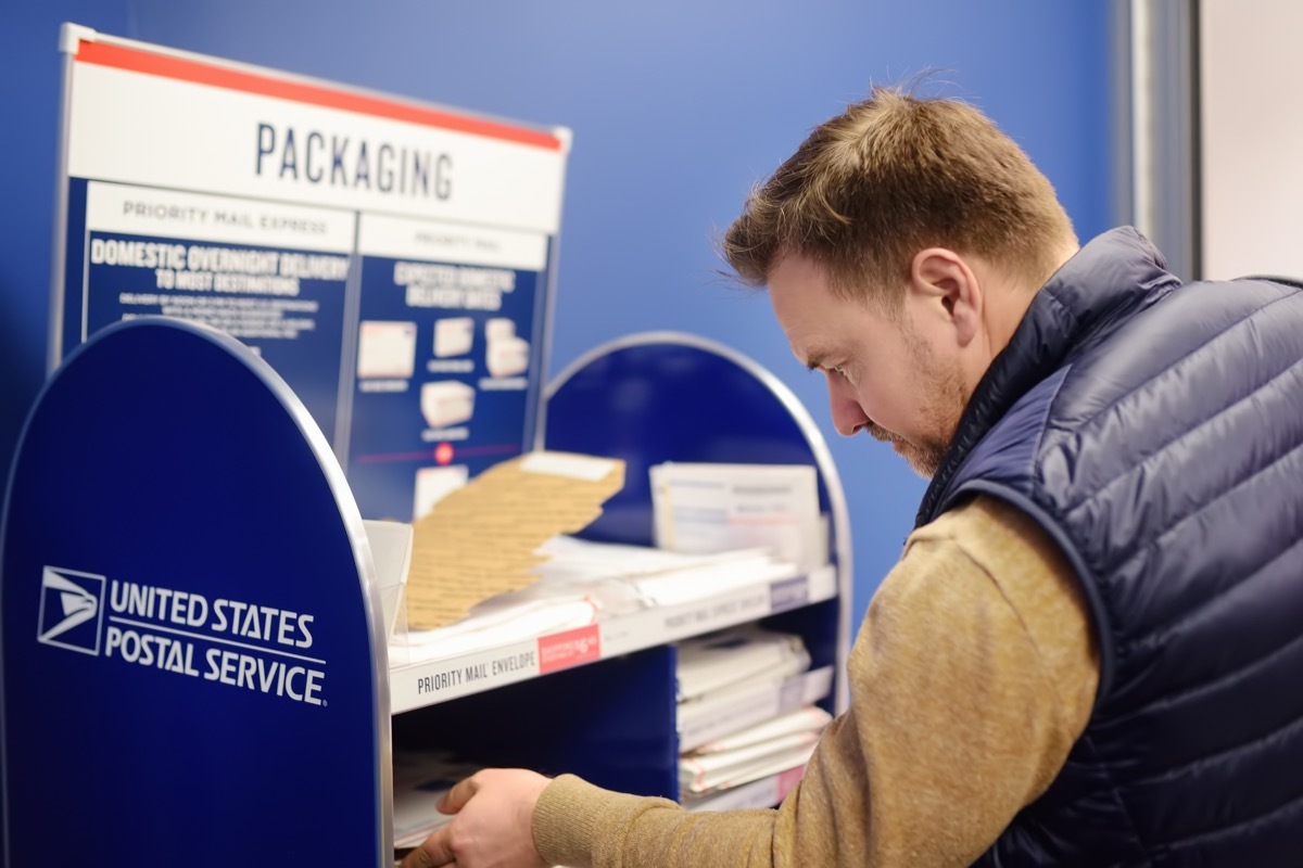 Mature man at the post office chooses an packaging - envelope or box for mailing. Postal system of the United States