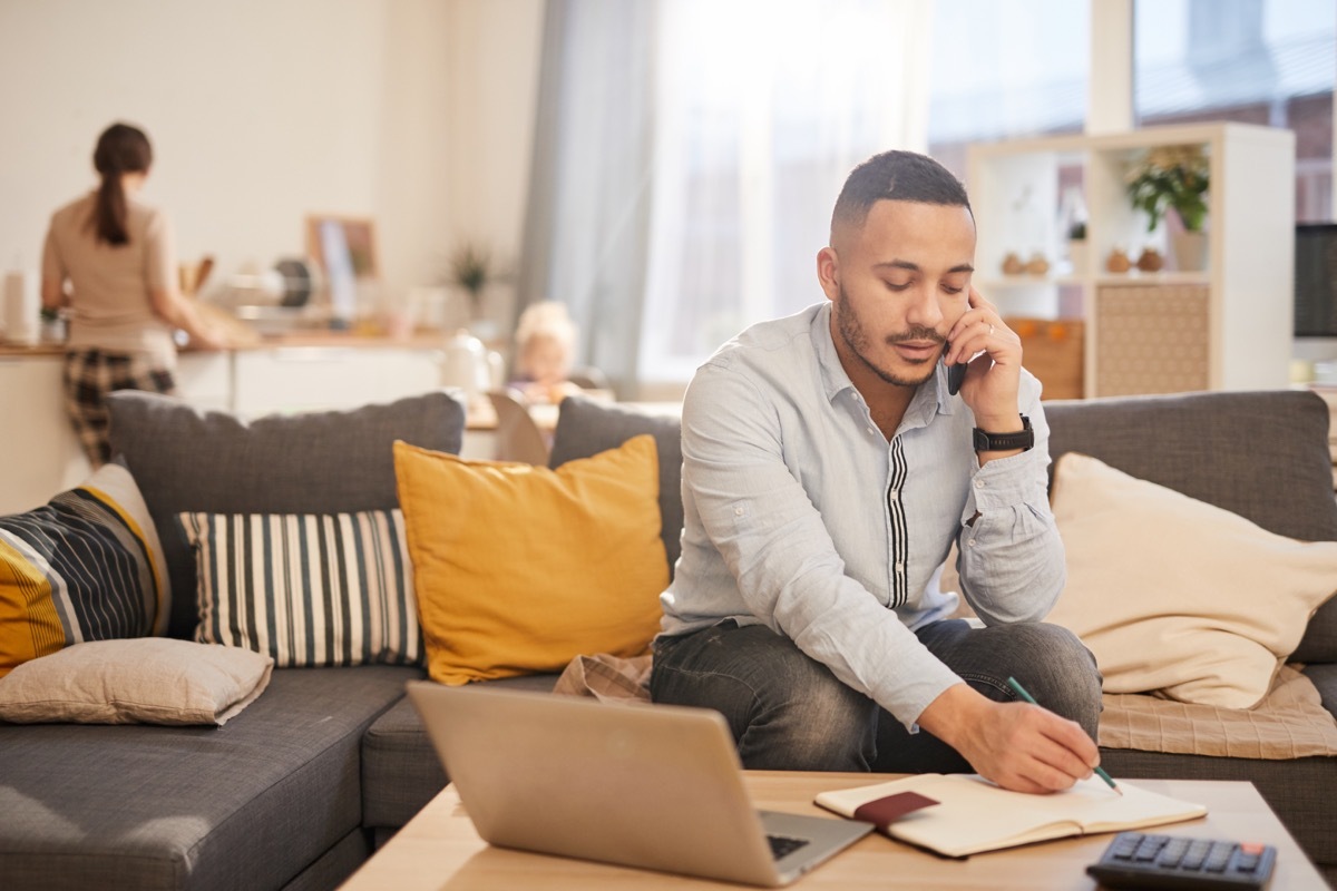 Portrait of speaking by phone while working from home in cozy interior, copy space