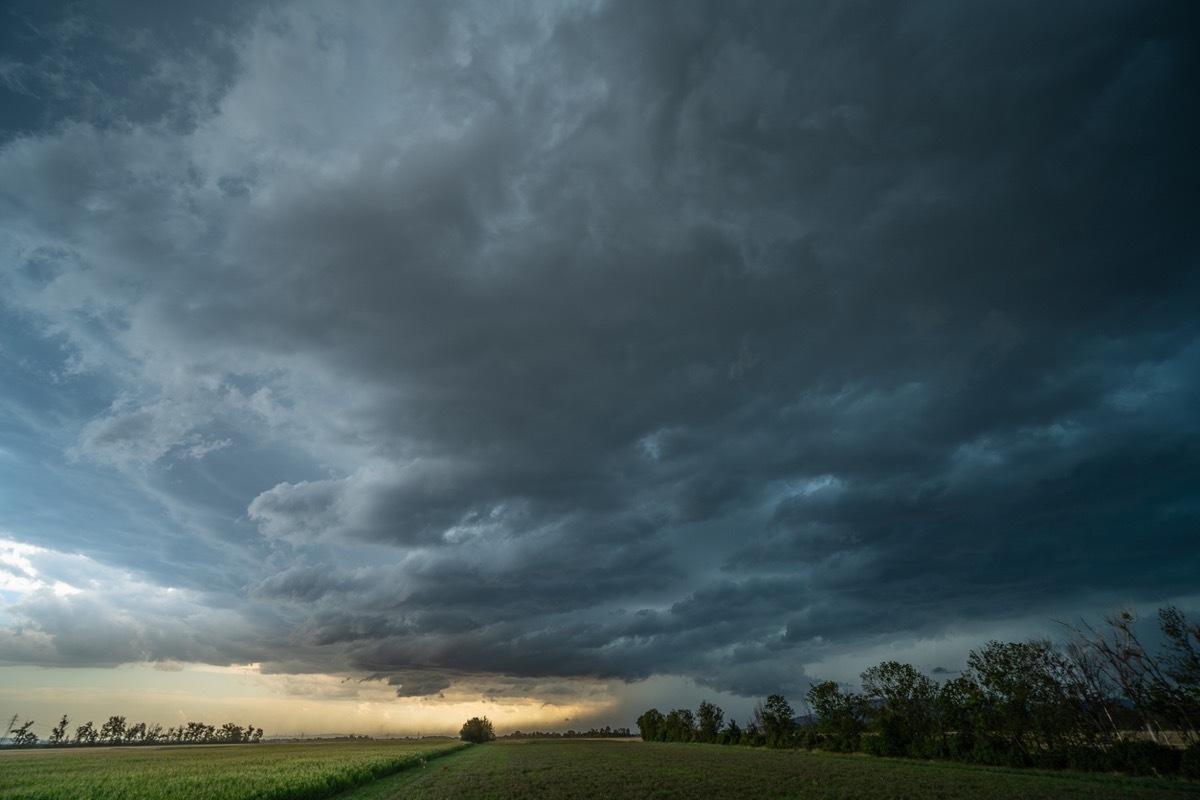 Dramatic sky over rural landscape, agricultural fields, approaching thunderstorm with dark storm clouds