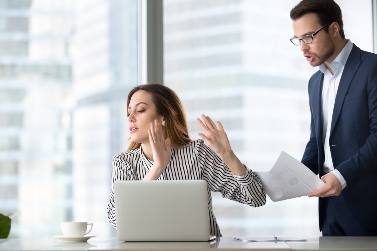 annoyed white woman at work rejecting a document from her male coworker