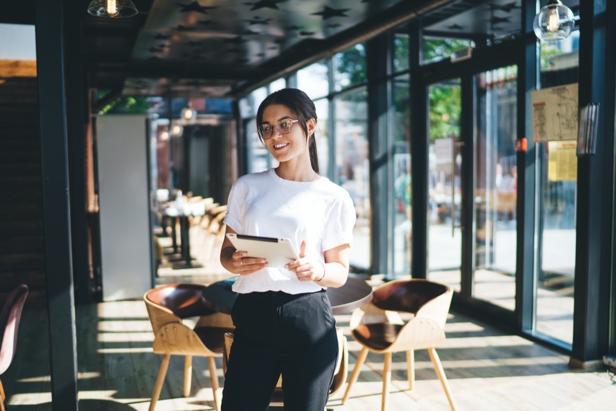 Female host in restaurant holding ipad