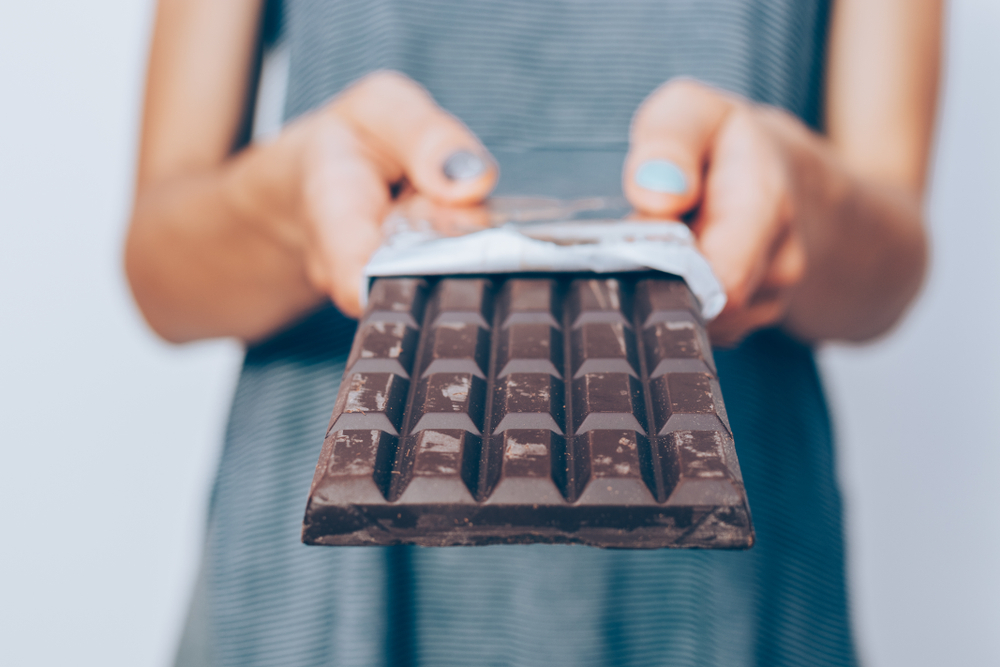 Close up of a person's hands holding a large bar of dark chocolate