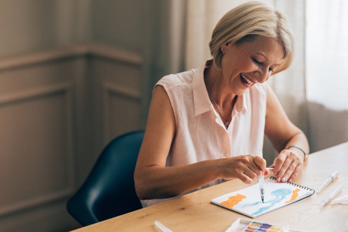 female expressing her creativity using watercolours. She is sitting at the desk.