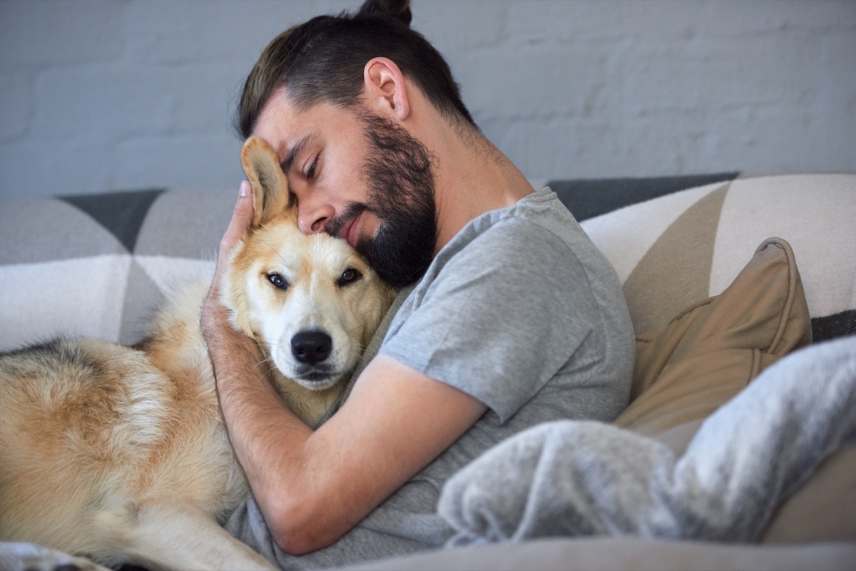 young white guy hugging upset dog