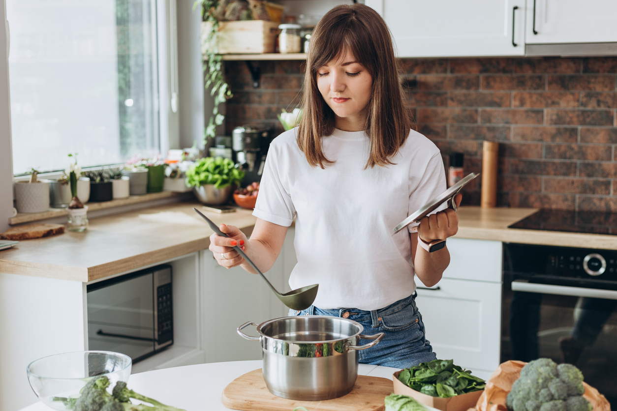 A young woman making soup in a kitchen