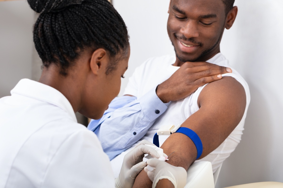 Close-up Of Female Doctor Injecting Male Patient With Syringe To Collect Blood Sample