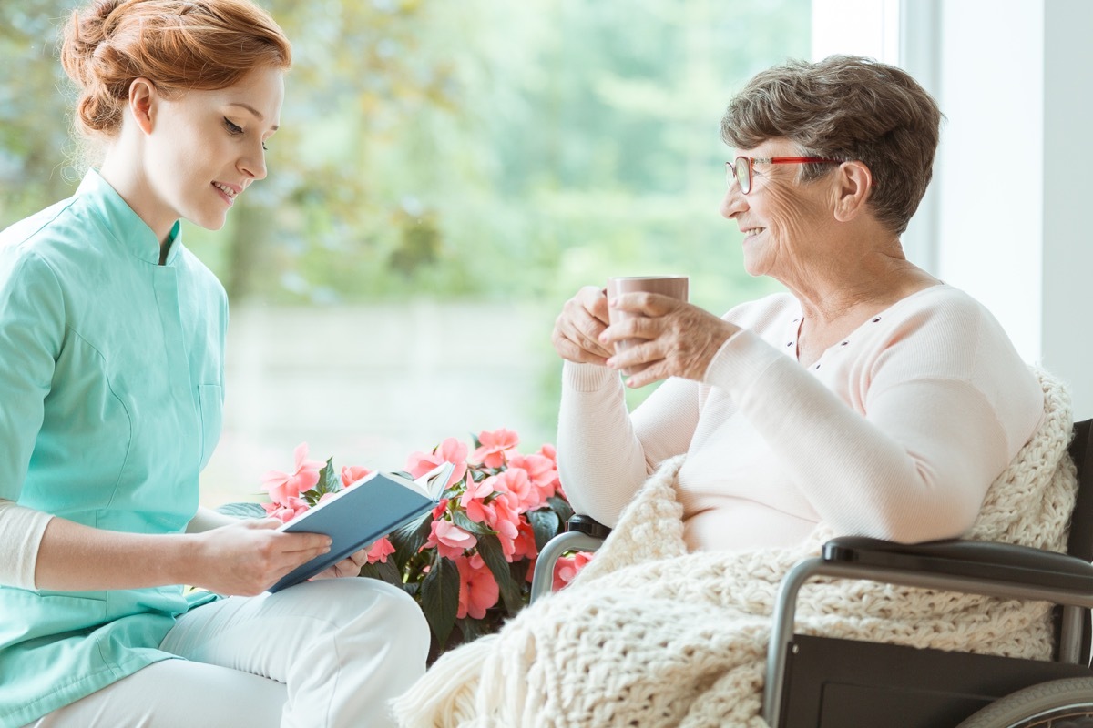 Young woman volunteering at the hospital reading to a patient