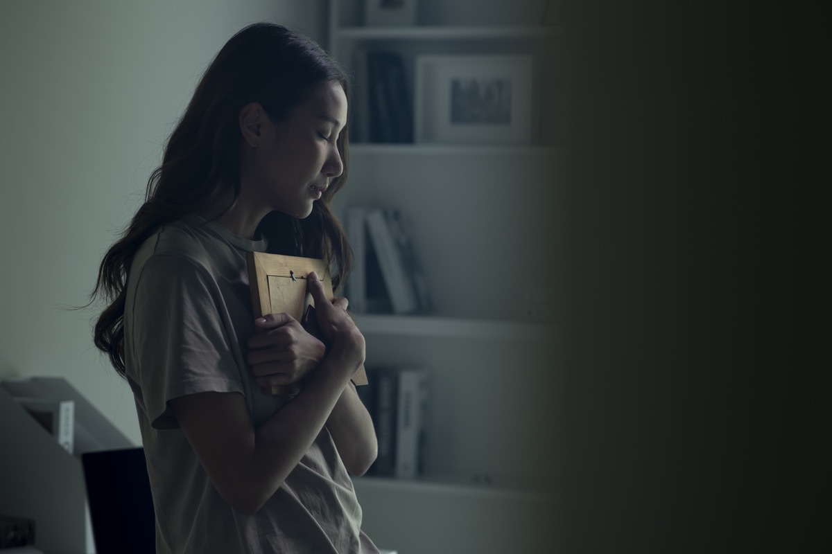 Woman feeling sad when looking at picture of lost loved one in the frame. Depressed