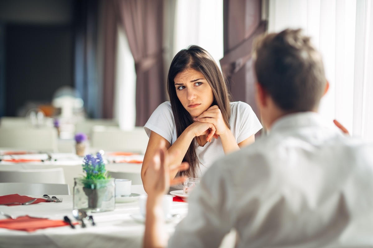 Woman and man sit at a restaurant having an argument.